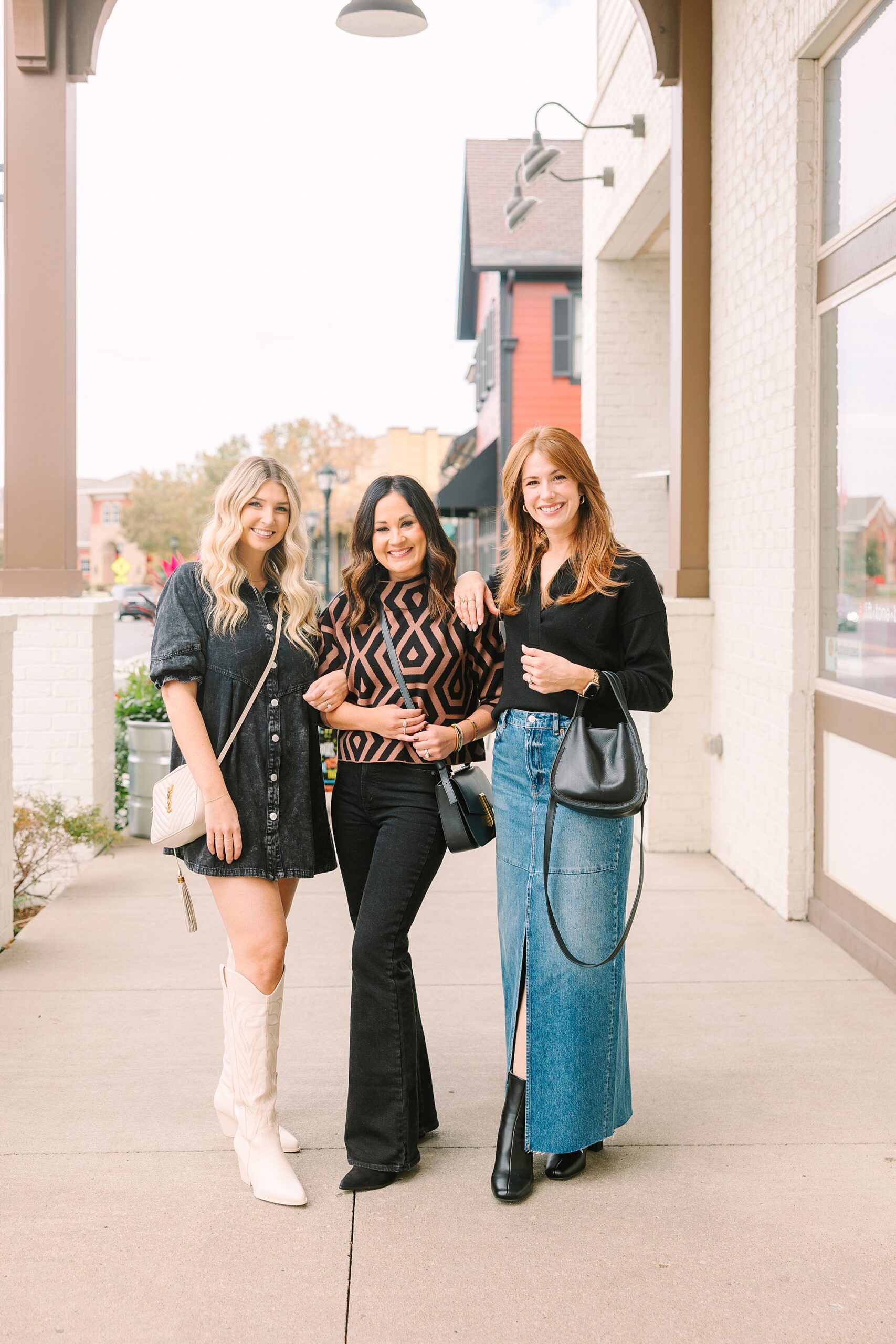 three women hug on sidewalk in chic outfits during quarterly Nashville branding session for Be Styled Co.