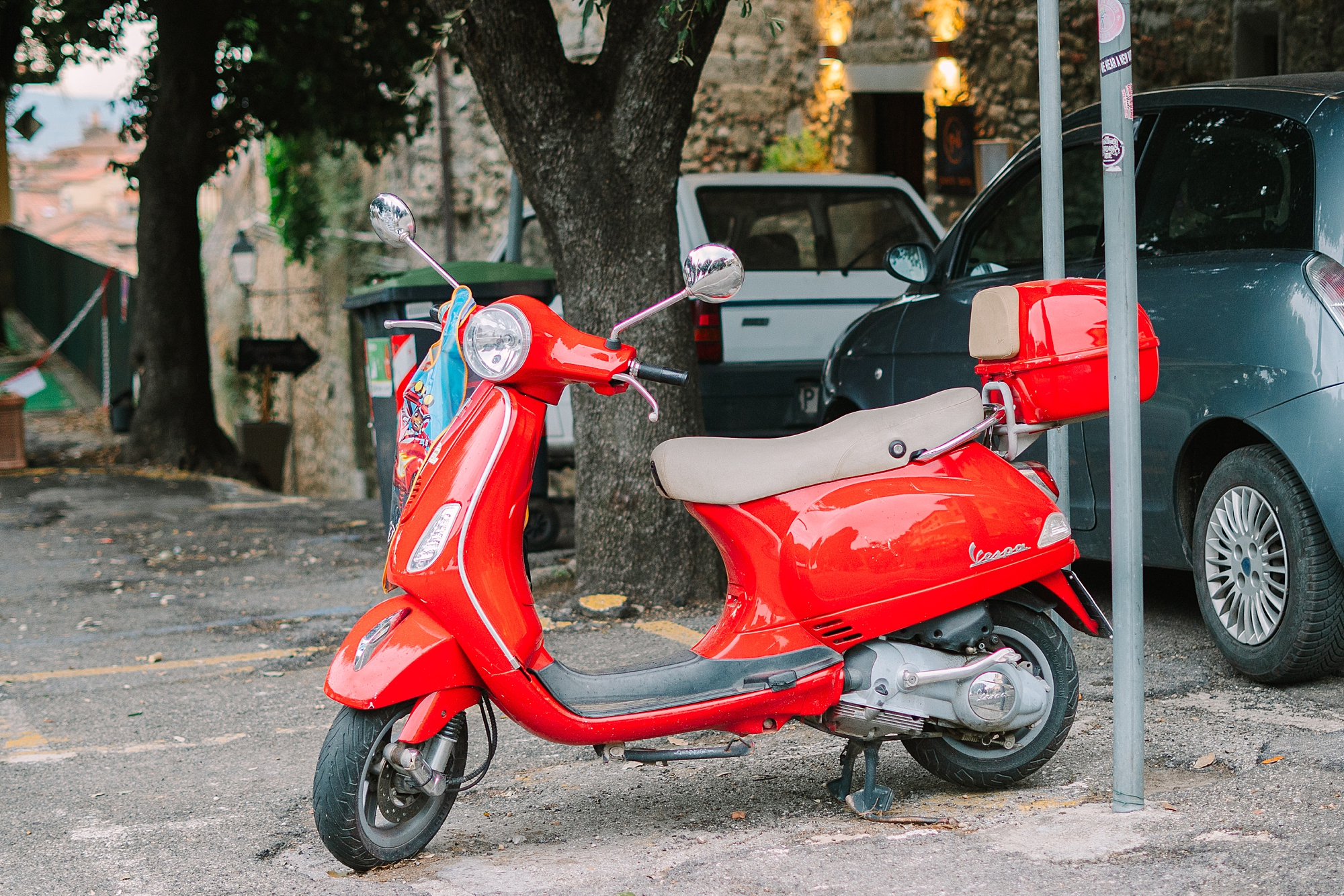 red Vespa parked on street in Italy