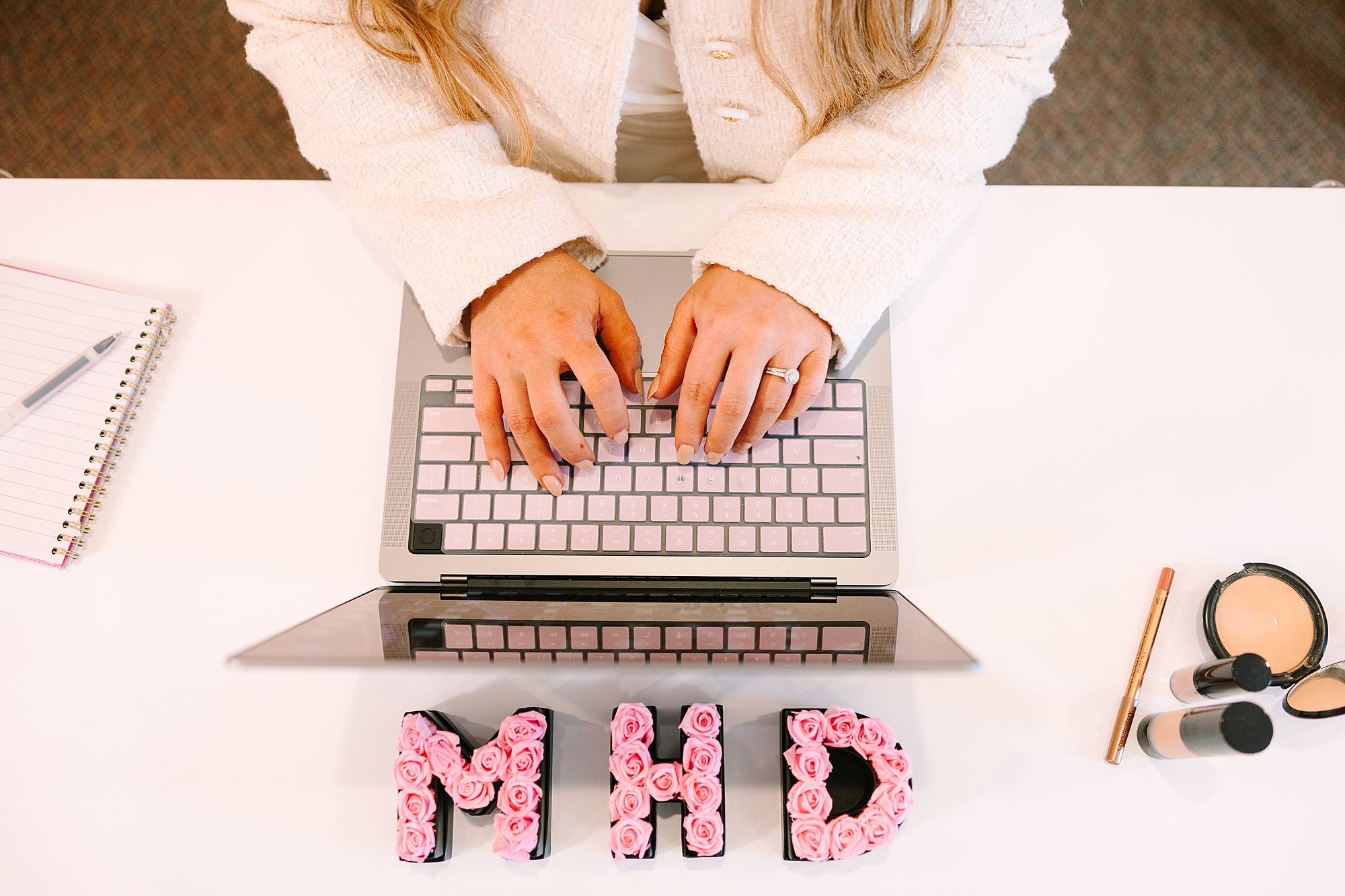 woman types on laptop with lipsticks making MHD in front of her