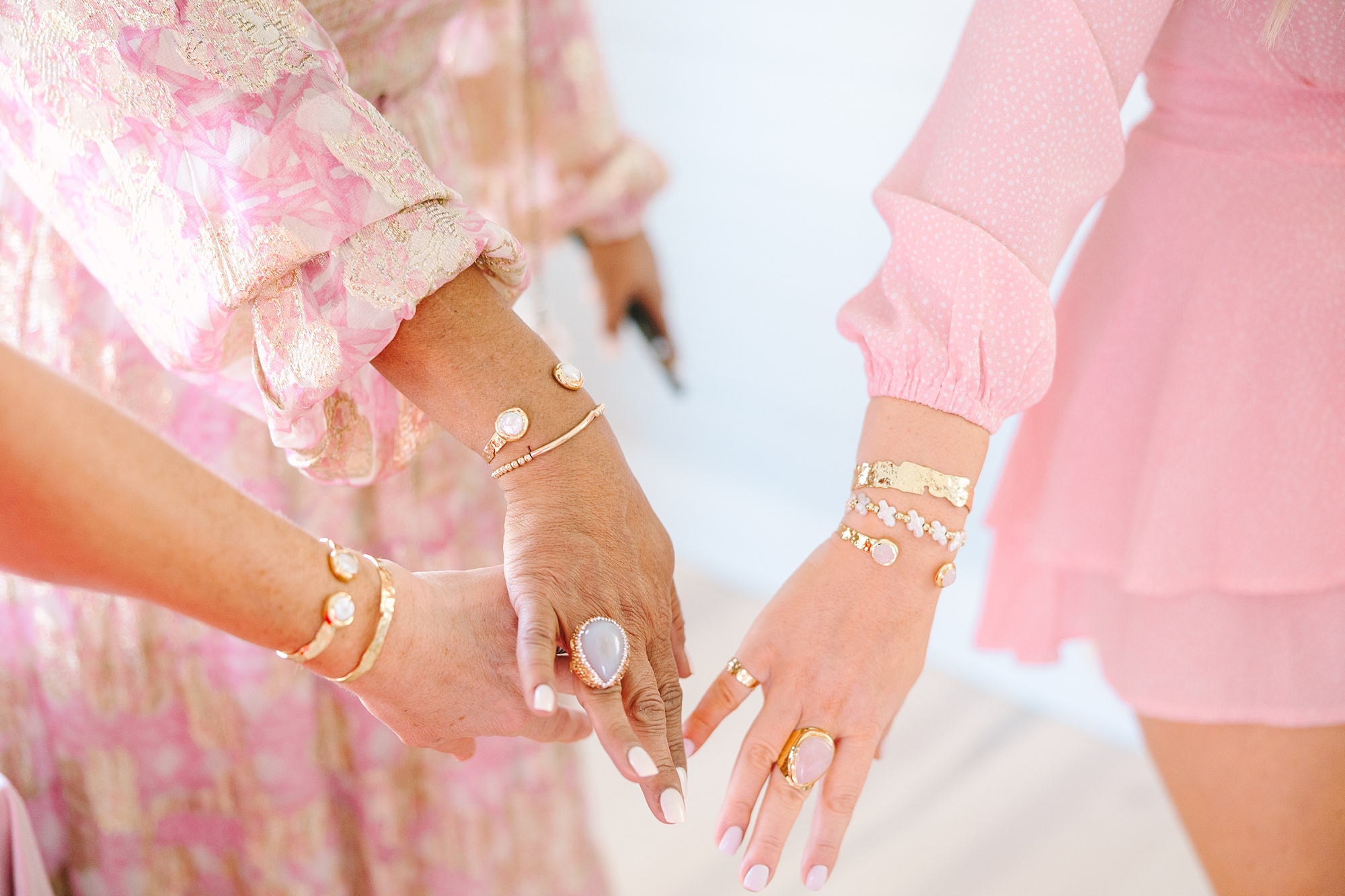 women in pink dresses show off gold jewelry for Galentine's Day Tea