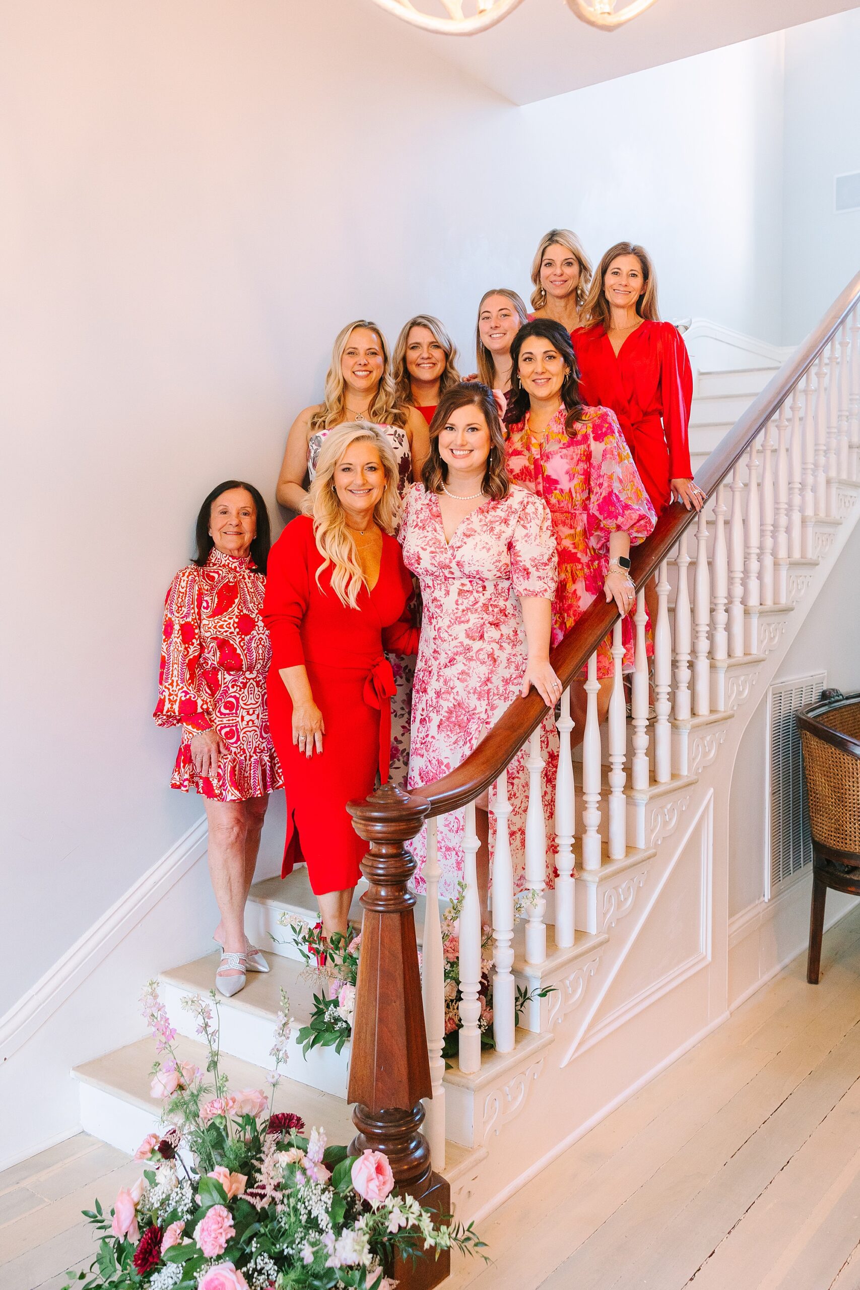 women pose on steps in red dresses during Galentine's Day Tea hosted by Pretty Lovely Teas