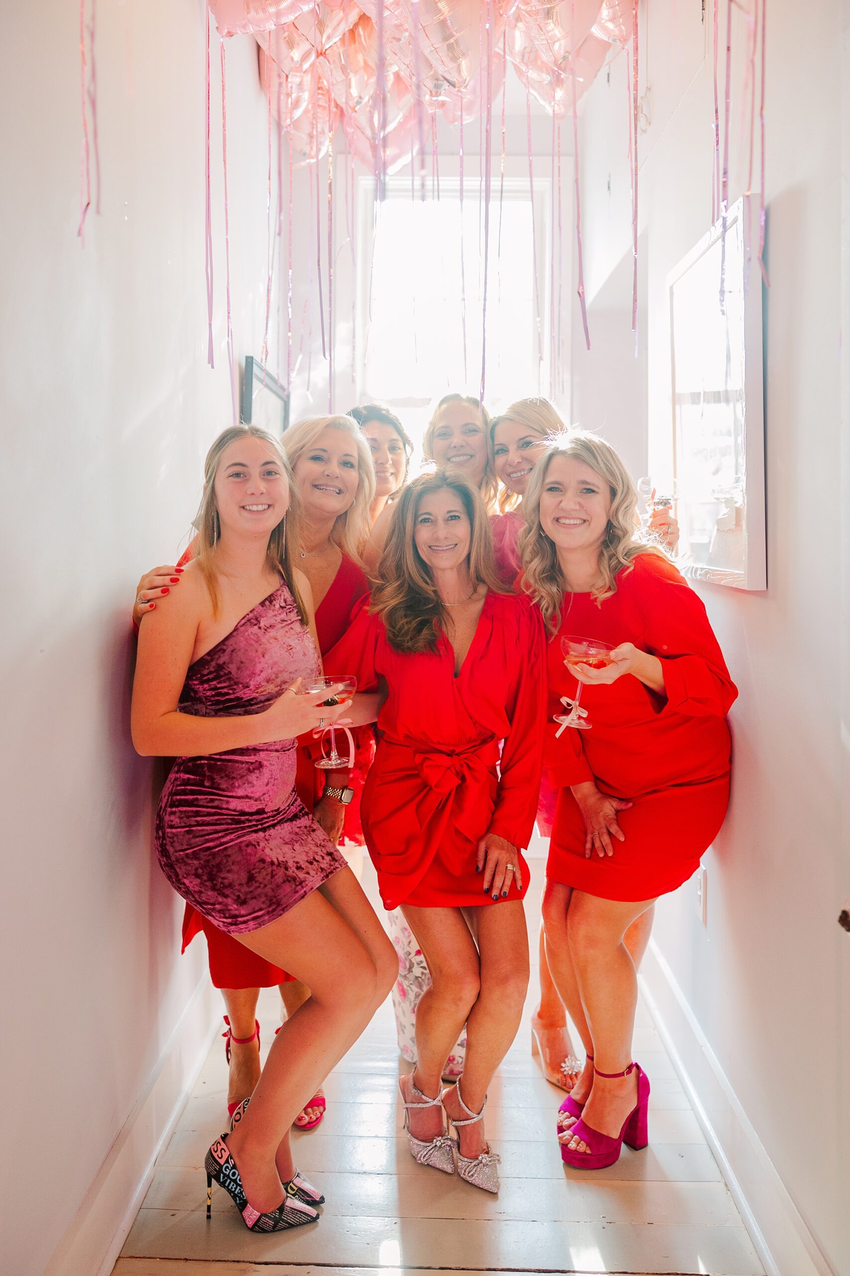 women in red dresses pose in hallway of Magnolia Acres