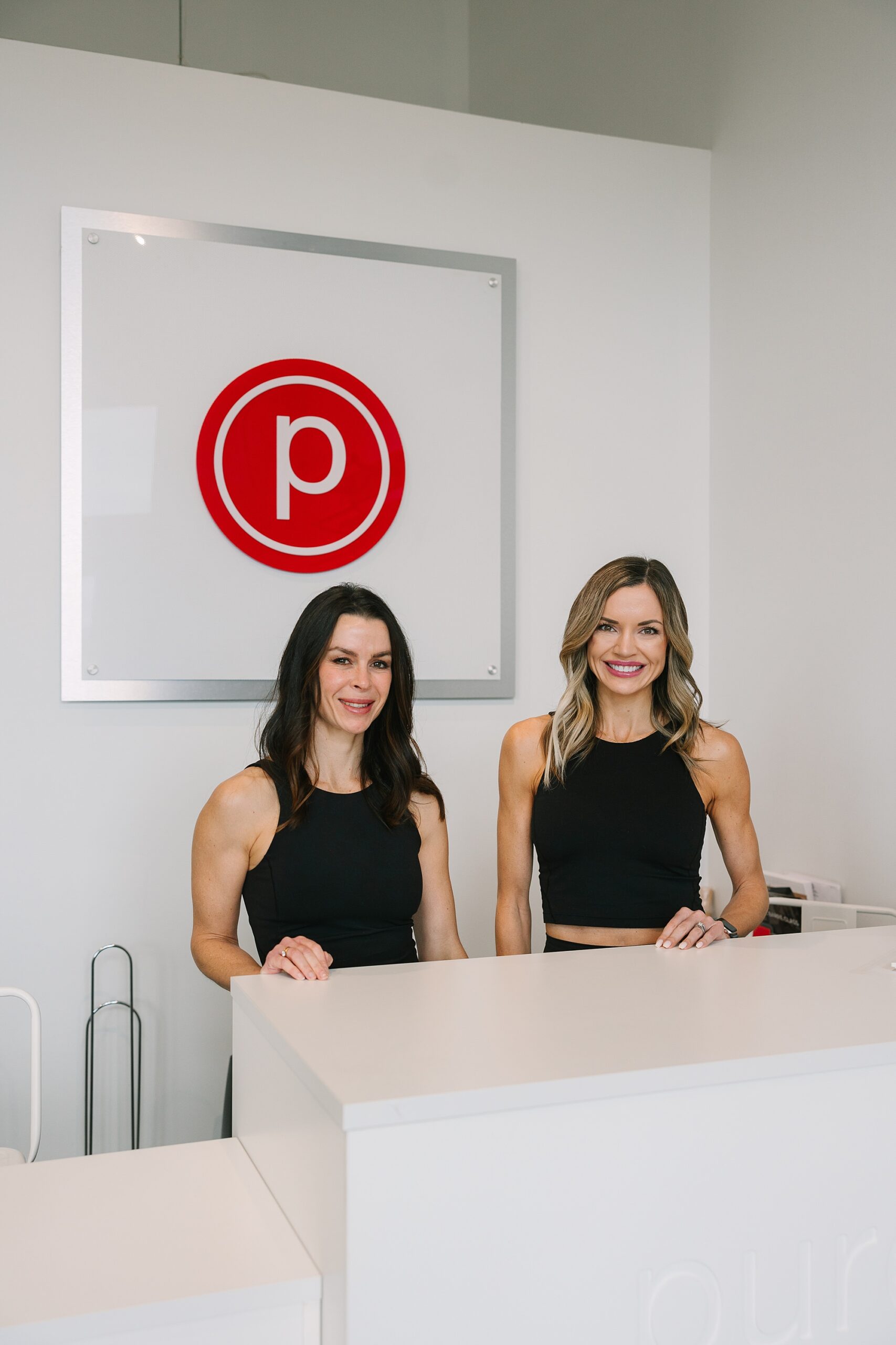 owners of Pure Barre Westhaven stand behind desk in lobby