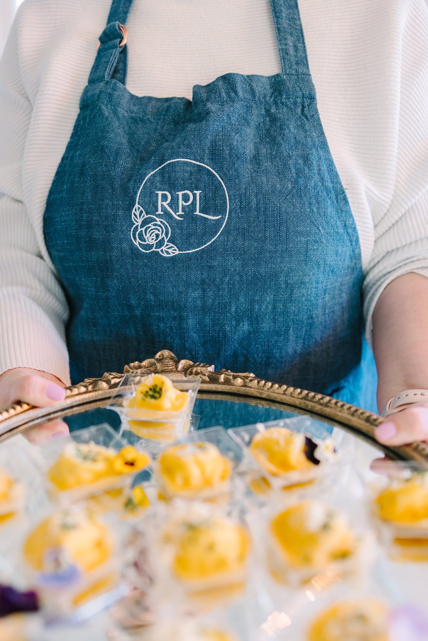 chef in blue apron holds out deviled eggs during menu tasting at Magnolia Acres for Rose & Plum Living