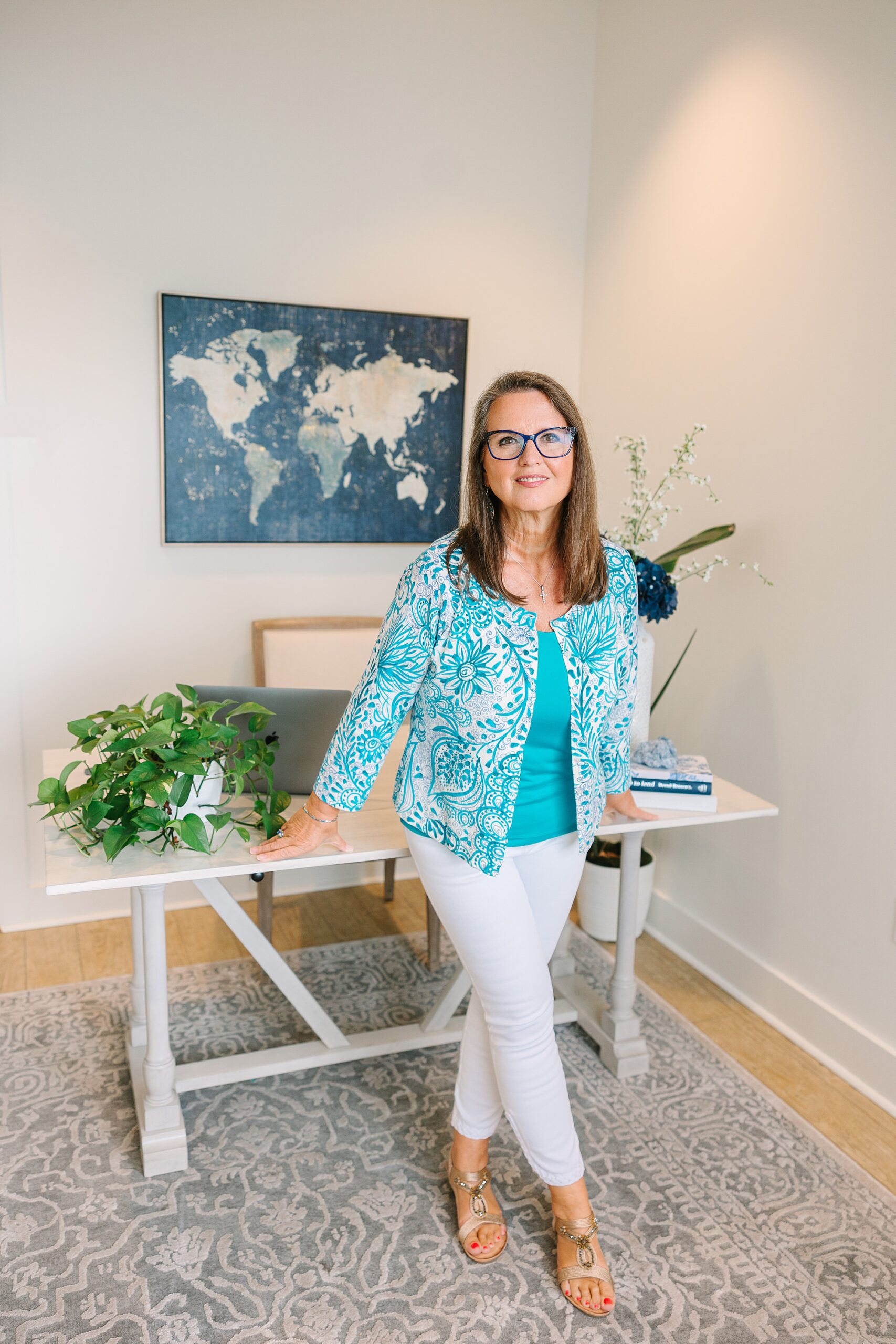 woman in blue sweater leans against standing desk at branding session at the Sapphire Suite