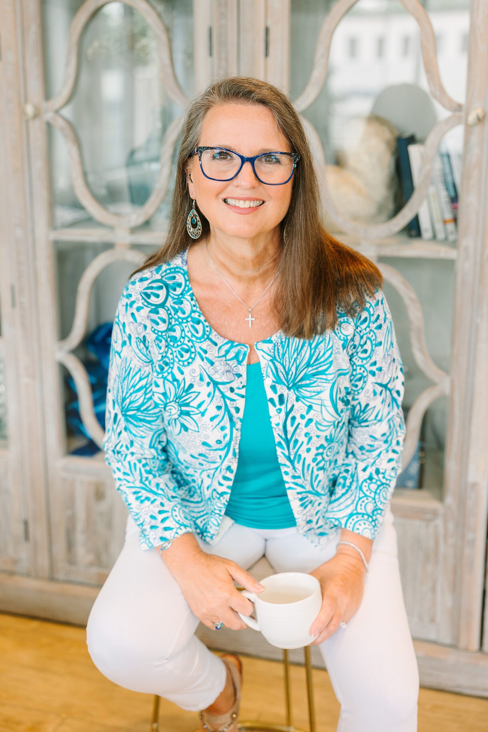 woman in blue and white sweater sits in front of cabinet at branding session at the Sapphire Suite