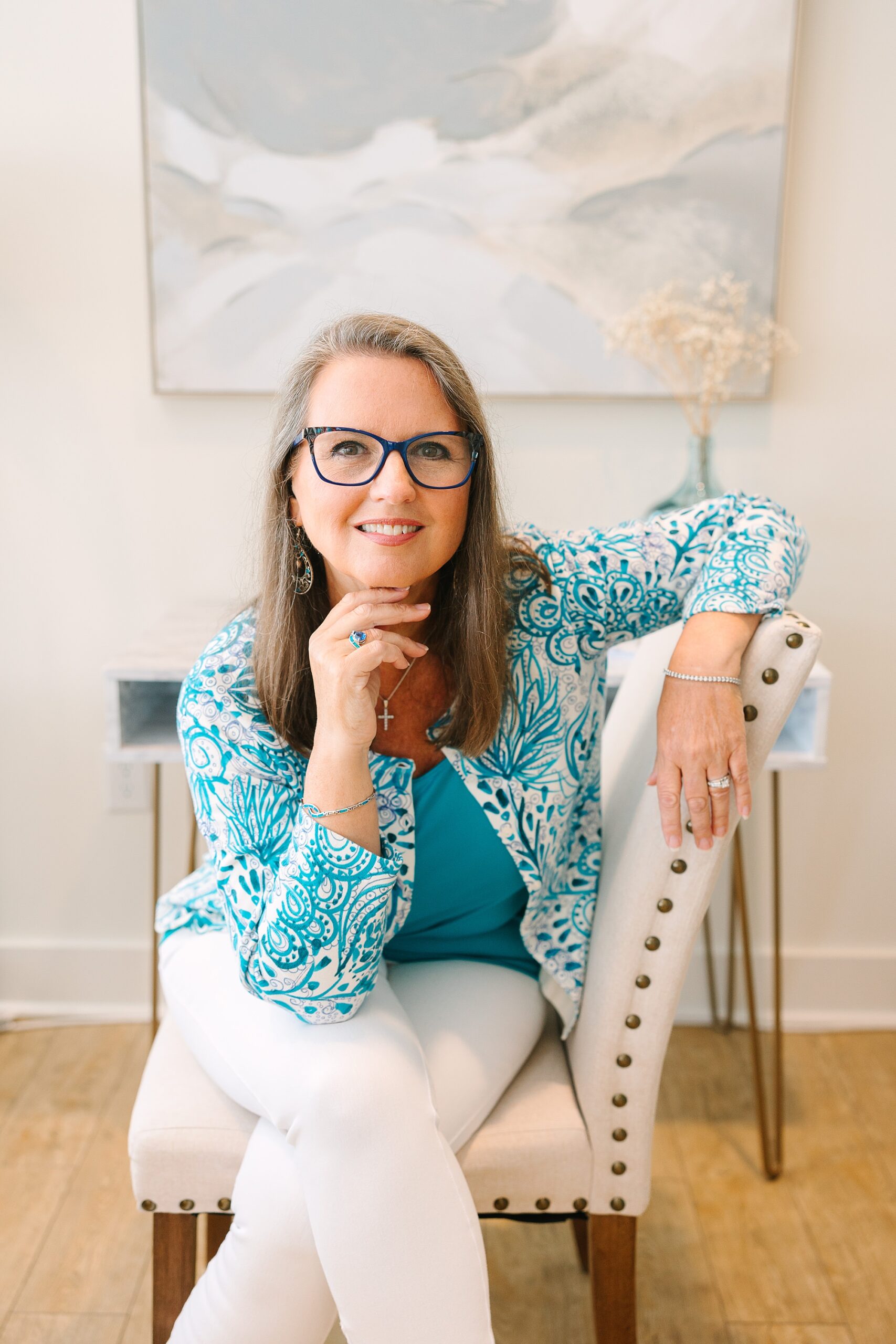 woman leans on back of white chair during branding photos at the Sapphire Suite